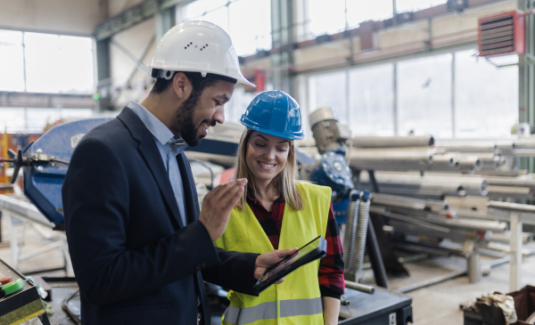 An engineering manager and mechanic worker doing routine check up in industrial factory and having video call.