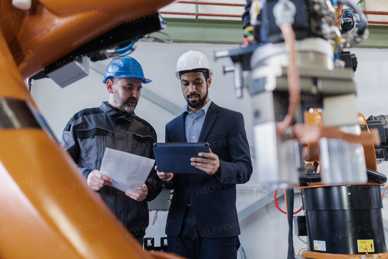 An engineering manager and mechanic worker doing routine check up in industrial factory