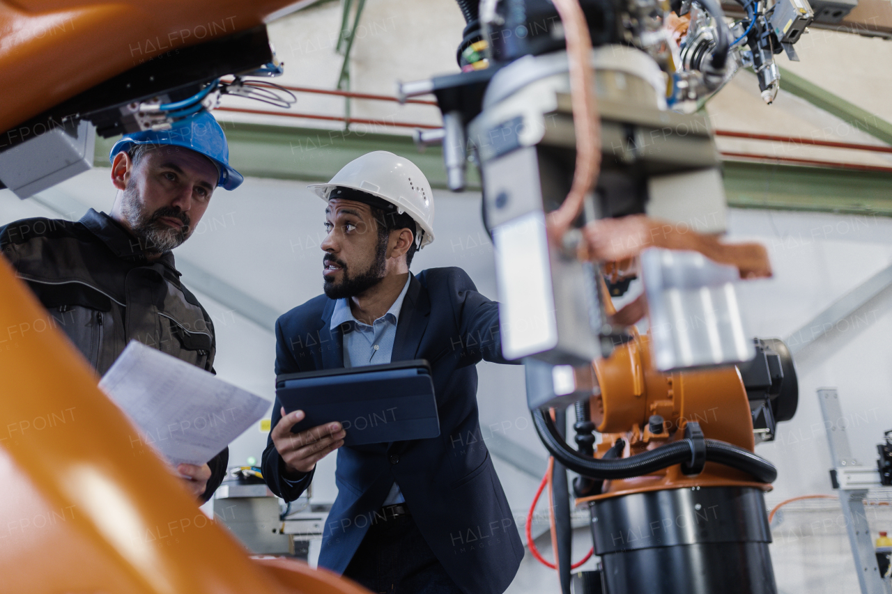 An engineering manager and mechanic worker doing routine check up in industrial factory