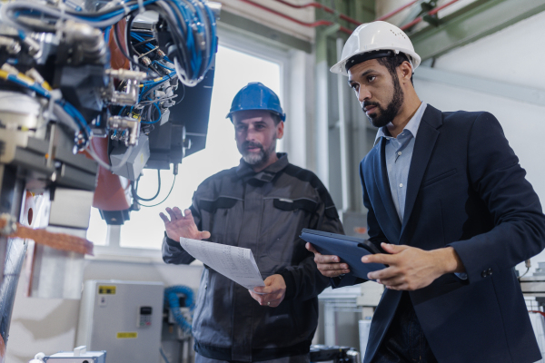 An engineering manager and mechanic worker doing routine check up in industrial factory