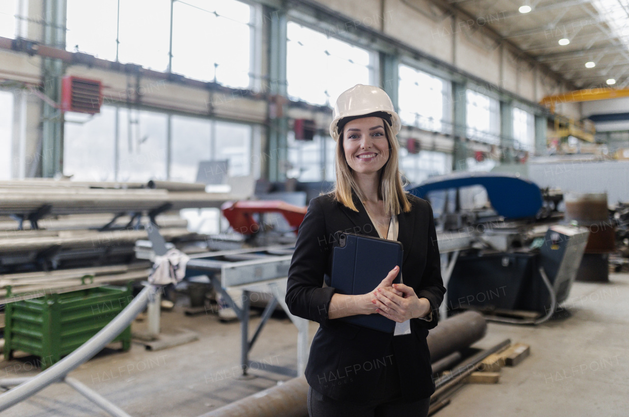 A portrait of female chief engineer in modern industrial factory using tablet.