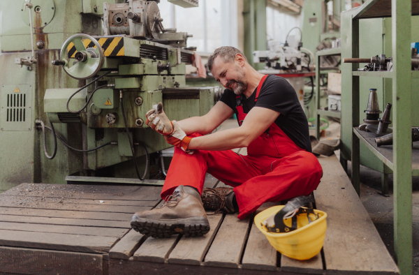 A eorker suffering from pain after accident in factory. First aid support on workplace concept.