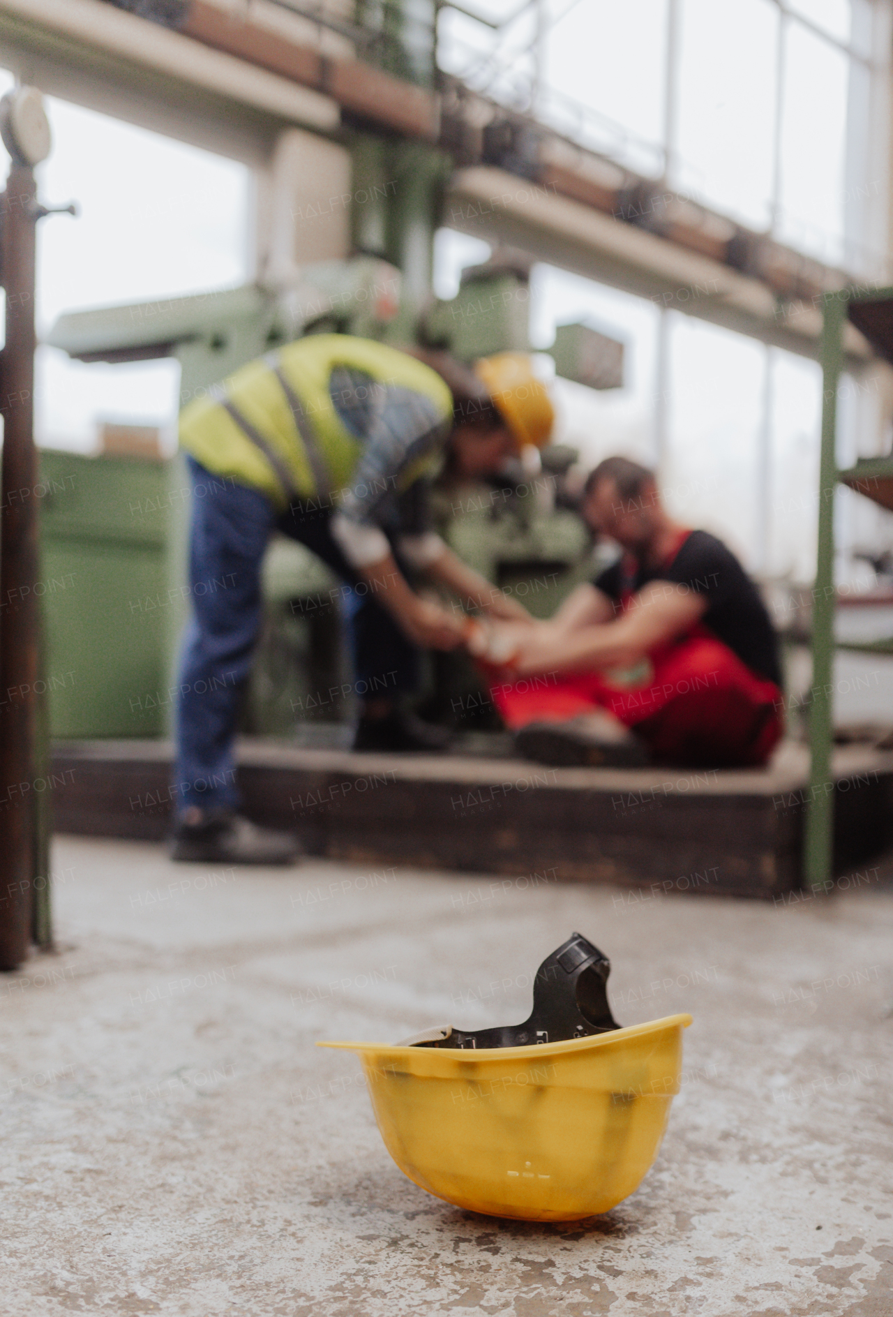 A woman is helping her colleague after accident in factory. First aid support on workplace concept.