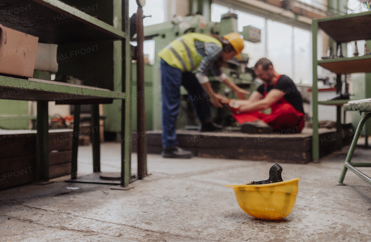 A woman is helping her colleague after accident in factory. First aid support on workplace concept.