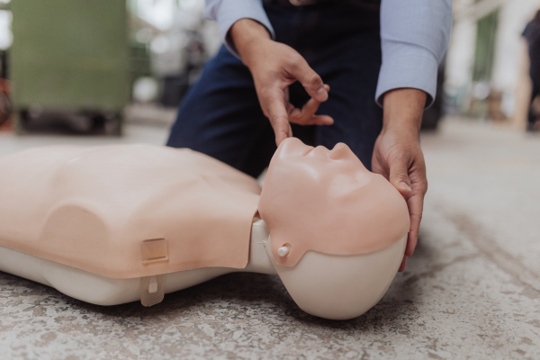 A close-up of male instructor showing first medical aid on doll during training course indoors