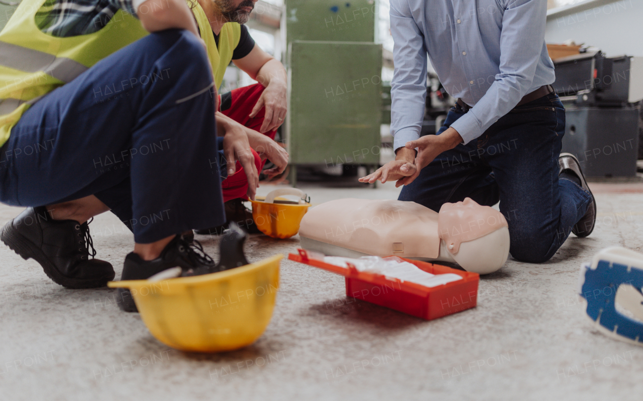 A male instructor showing first medical aid on doll during training course indoors