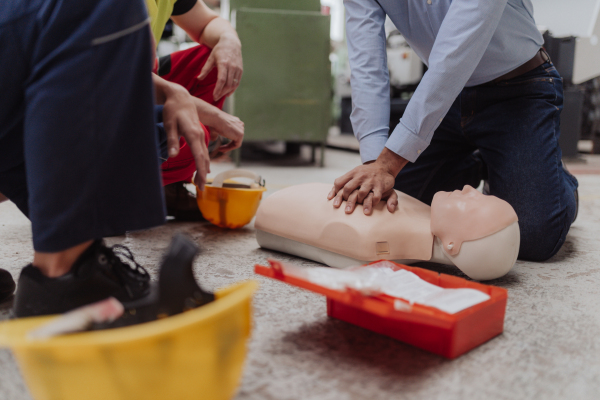 A male instructor showing first medical aid on doll during training course indoors, close-up