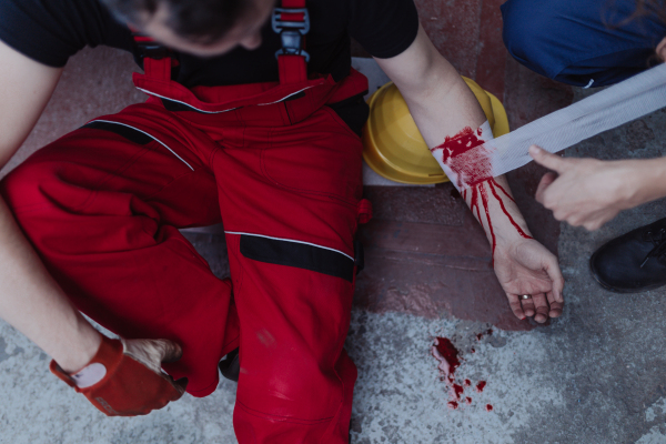 A woman is helping her colleague after accident in factory. First aid support on workplace concept.