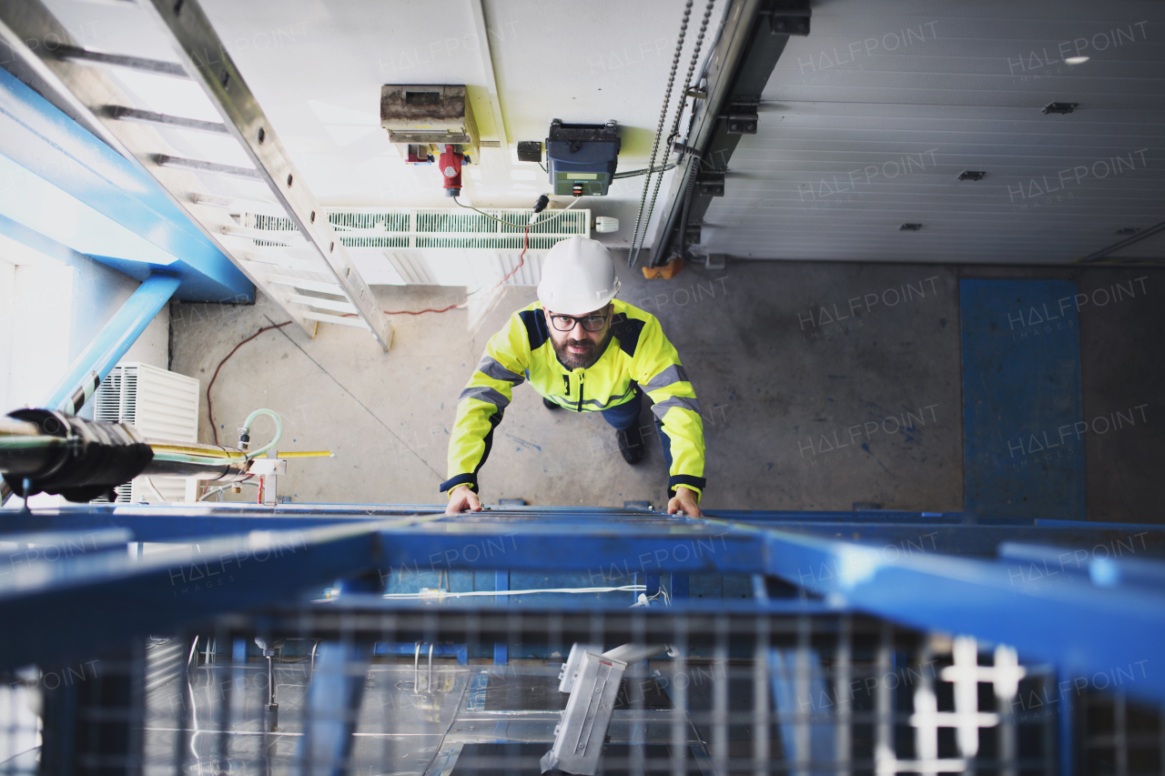 A top view of engineer in industrial factory climbing up the ladder.