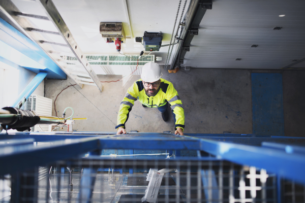 A top view of engineer in industrial factory climbing up the ladder.