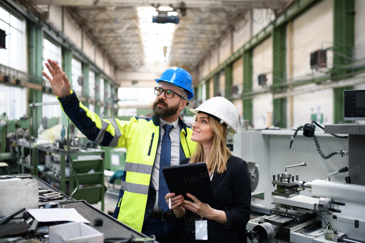 A male and female industrial engineers discussing factory's new machinery project and using laptop.