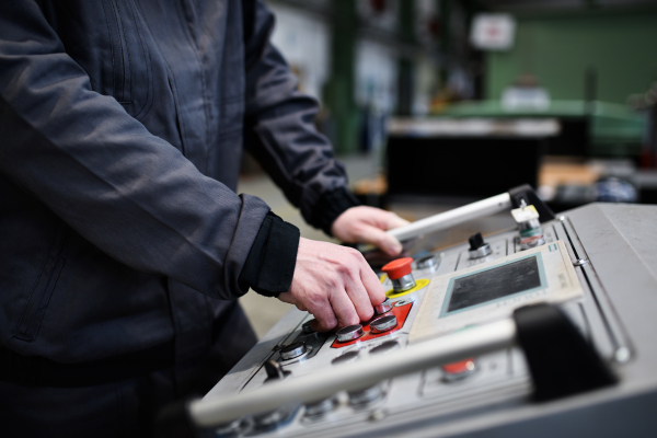 Close-up of an engineer working at machine in industrial factory