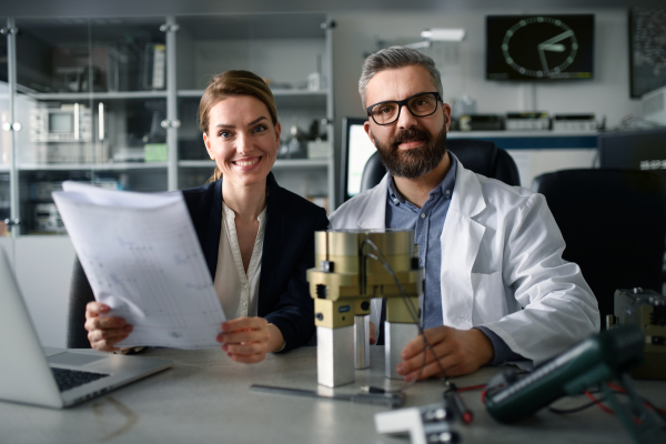 Robotics engineers working on a laptop and desinging modern robotic arm in laboratory.