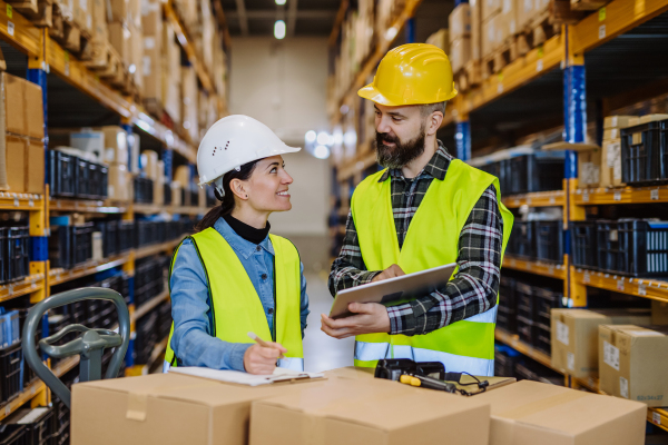 Warehouse workers checking stuff in warehouse with digital system in a tablet, holding a solar panel.