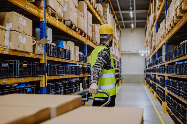 Male warehouse worker dragging the pallet truck.