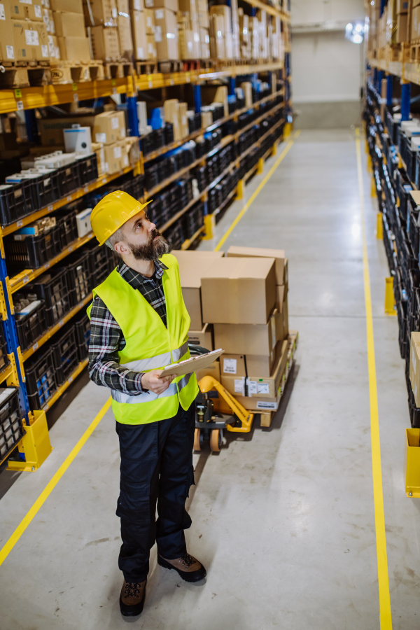 Male warehouse worker dragging the pallet truck.