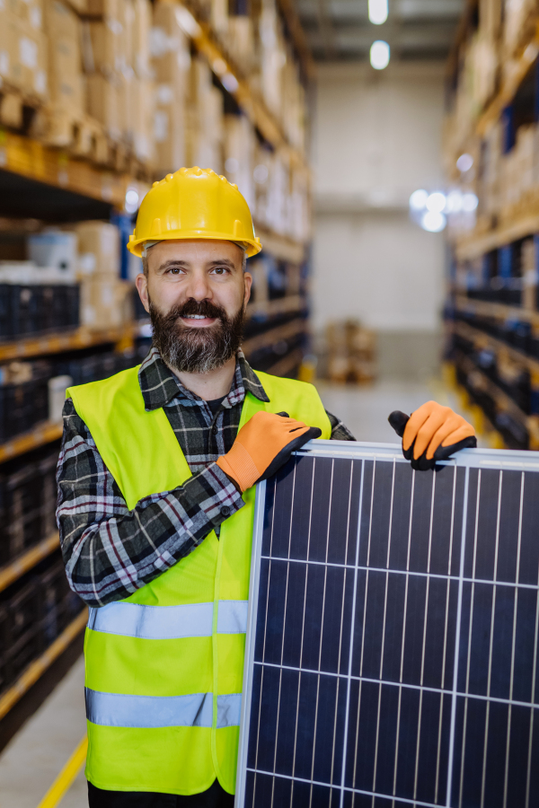 Portrait of warehouse worker with a solar panel.