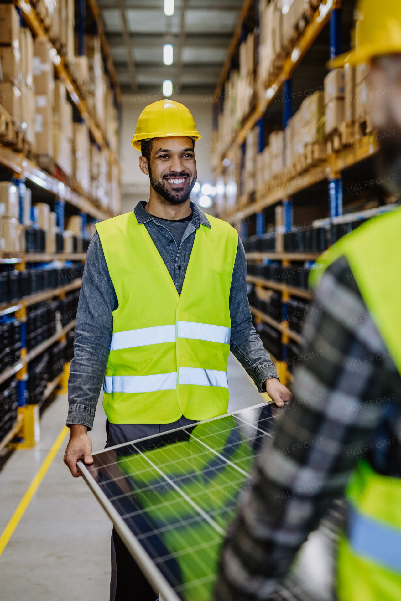 Happy warehouse workers carring a solar panel.