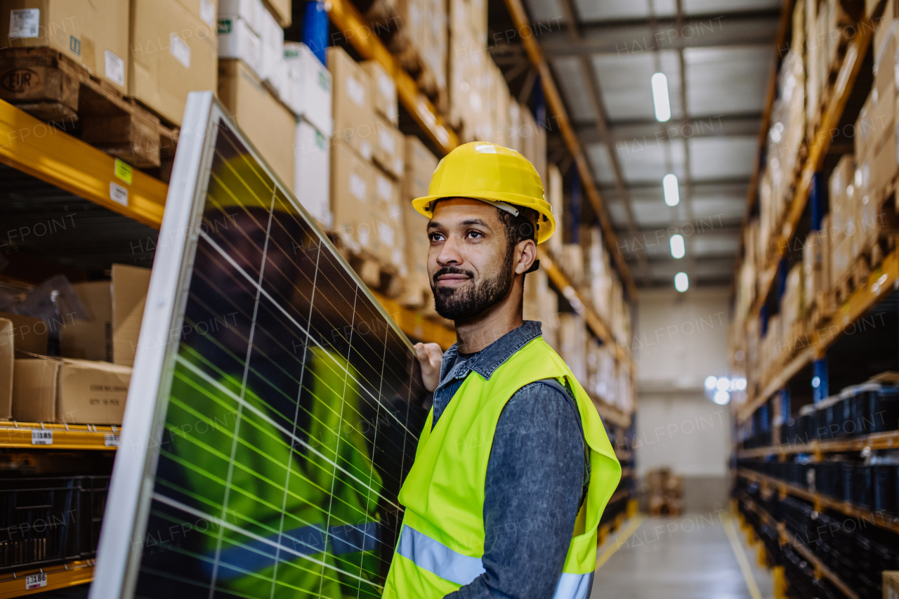 Portrait of warehouse worker carring a solar panel.