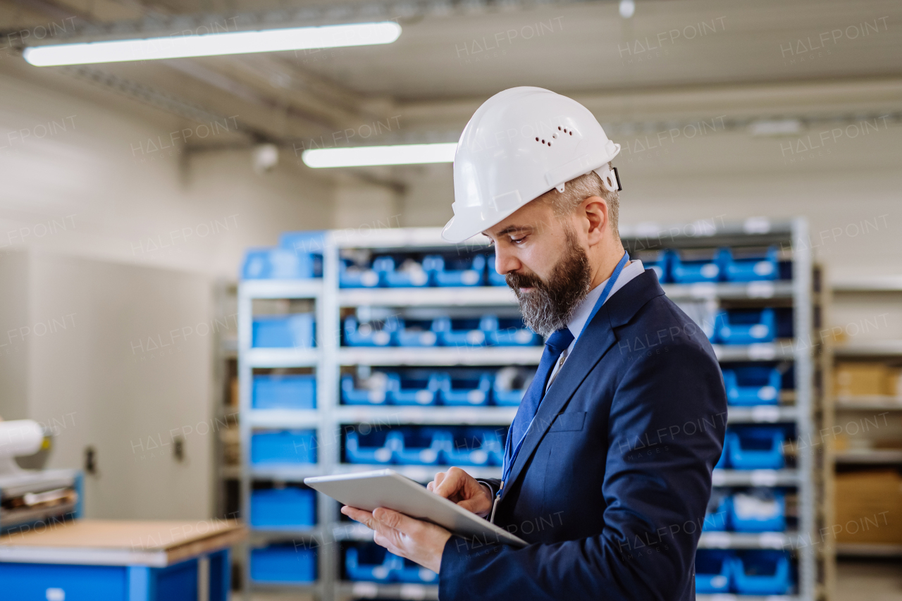 Manager in suit controlling goods in warehouse.