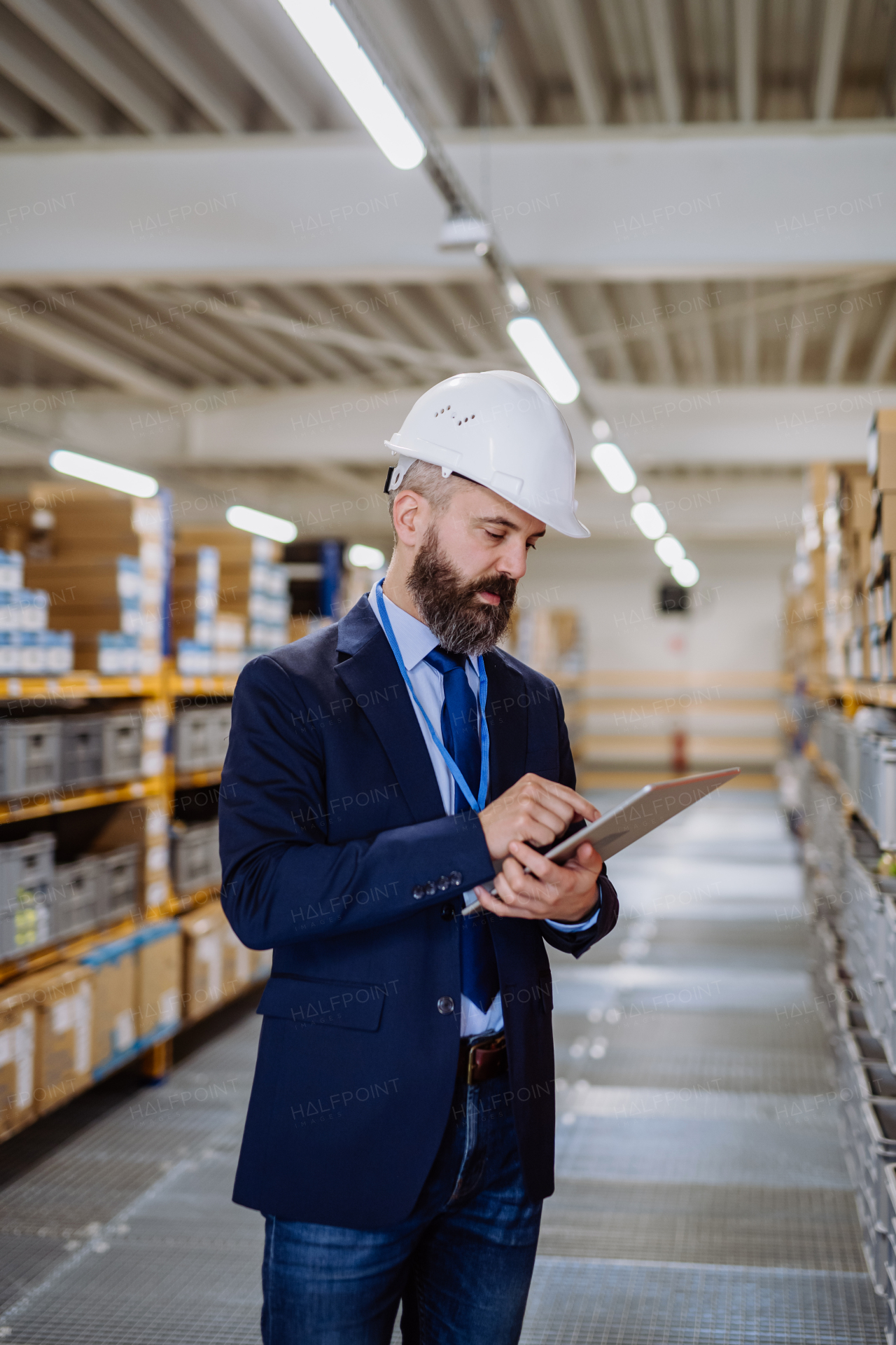 Manager in suit controlling goods in warehouse.