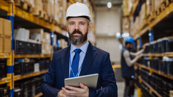 Manager in suit controlling goods in warehouse.