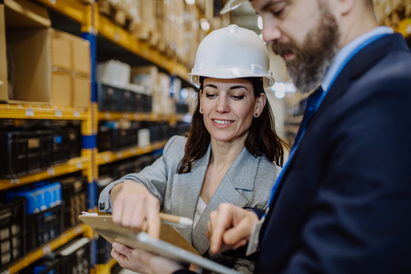 Managers in suit controlling goods in warehouse.