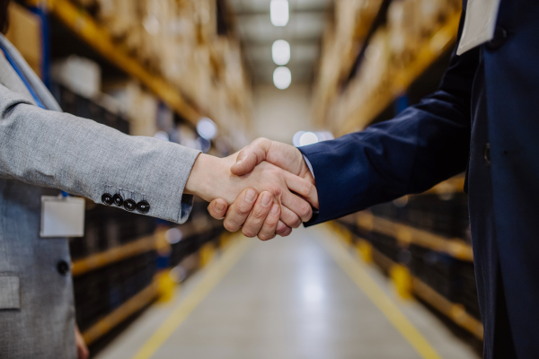 Close-up of managers shaking hands in a warehouse.