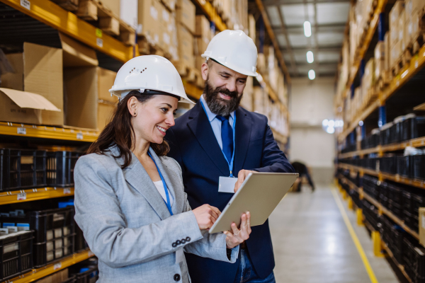 Managers in suit controlling goods in warehouse.