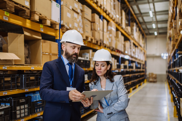 Managers in suit controlling goods in warehouse.