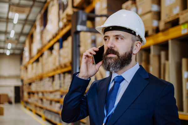 Manager woman in suit calling in warehouse.