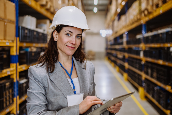 Manager woman in suit controlling goods in warehouse.