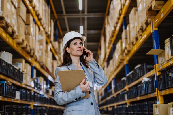 Manager woman in suit calling in warehouse.