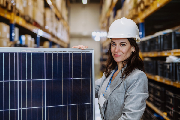 Portrait of manager holding solar panel in a warehouse.