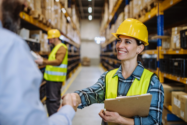 Manager shaking hands with employers in a warehouse.