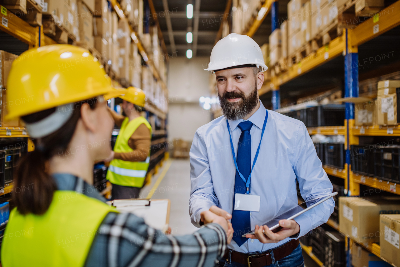 Manager shaking hands with employers in a warehouse.