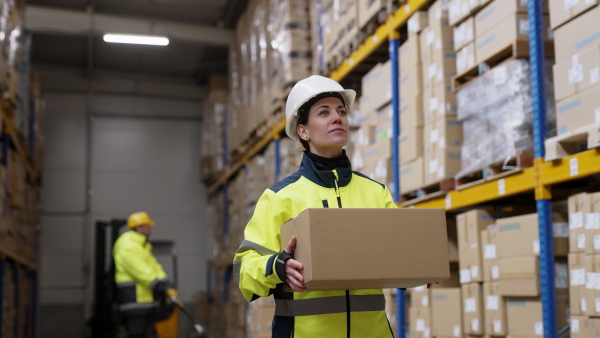 Female warehouse worker stocking goods in warehouse.