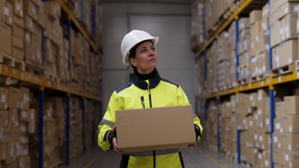 Female warehouse worker stocking goods in warehouse.