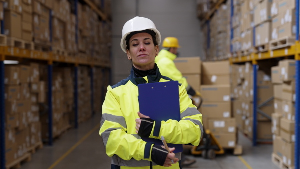 Video of a female warehouse worker or a supervisor walking towards the camera.