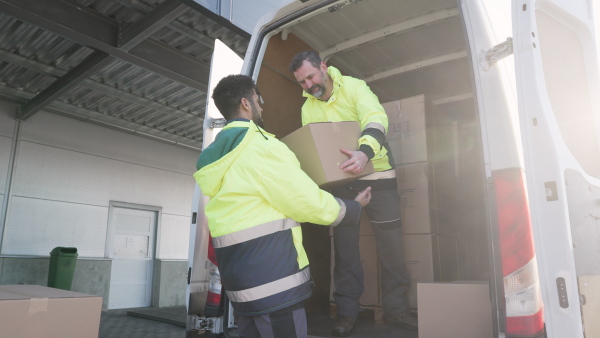 Warehouse workers unloading goods from van in a warehouse.