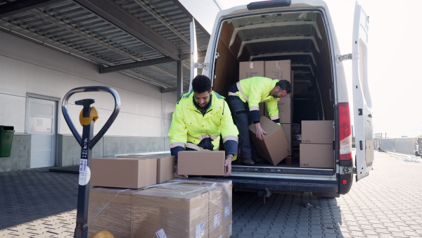 Warehouse workers unloading goods from van in a warehouse.