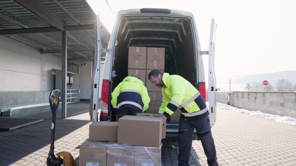 Warehouse workers loading goods to van in a warehouse.