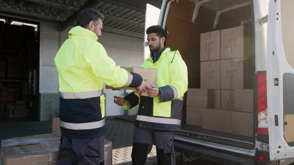 Warehouse workers loading goods to van in a warehouse.