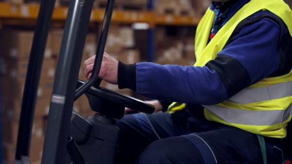 Close up of male warehouse worker using a fork lift.