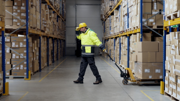 Male warehouse worker dragging the pallet truck.