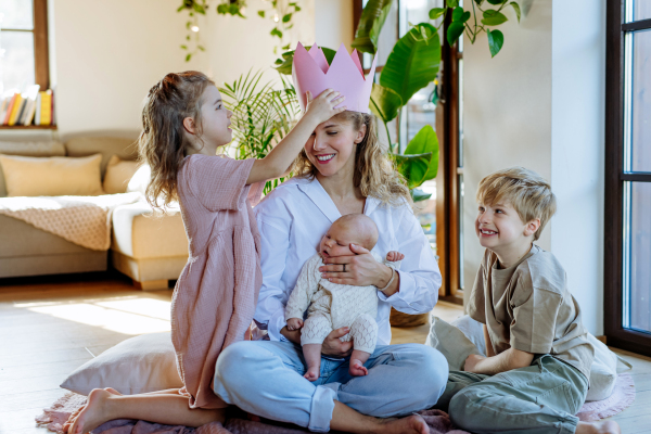 Mother after giving birth as a queen. Daughter giving mom a paper crown and admiration, love for mothers, concept of Mother's Day and women's strength.