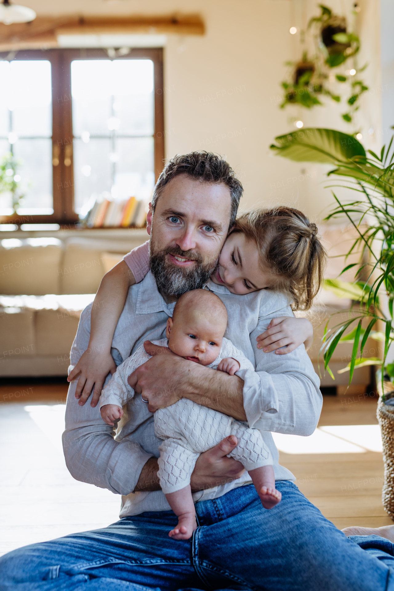 Father holding newborn baby girl, older daughter with them. New sibling. Girls dad. Unconditional paternal love and Father's Day concept.