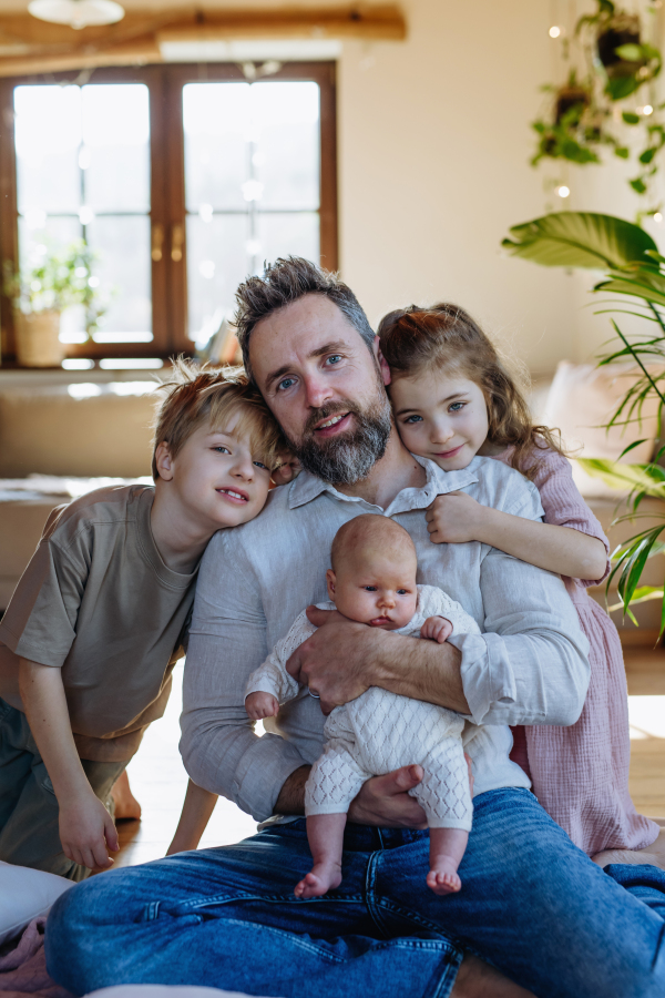 Portrait of father holding newborn baby, enjoying all his kids. New sibling. Unconditional paternal love and Father's Day concept.