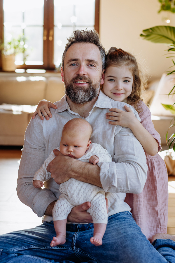 Father holding newborn baby girl, older daughter with them. New sibling. Girls dad. Unconditional paternal love and Father's Day concept.