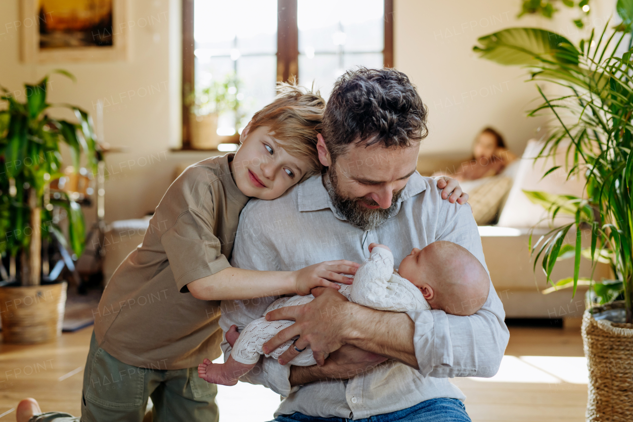 Father and boy holding newborn baby. New sibling. Unconditional paternal love and Father's Day concept.